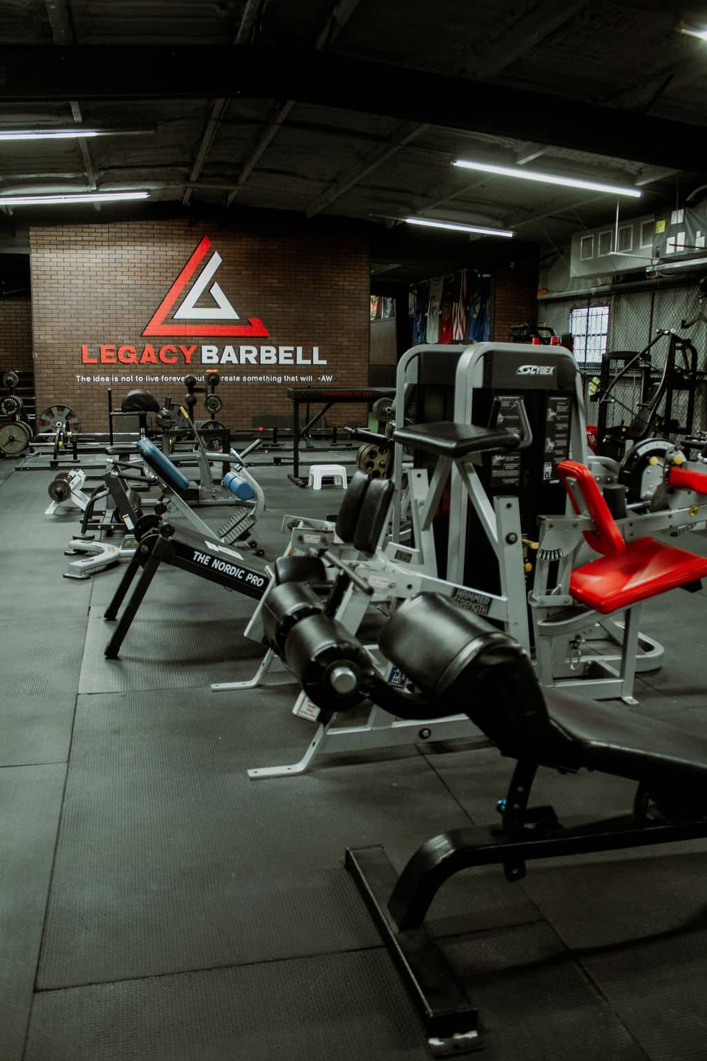 Legacy Barbell Sign on back wall of gym with gym equipment