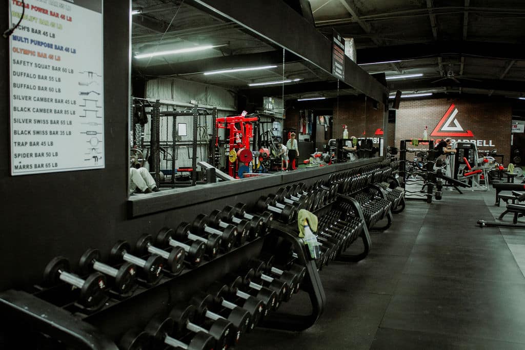 Legacy Barbell Free Weights Line Up with people working out in background